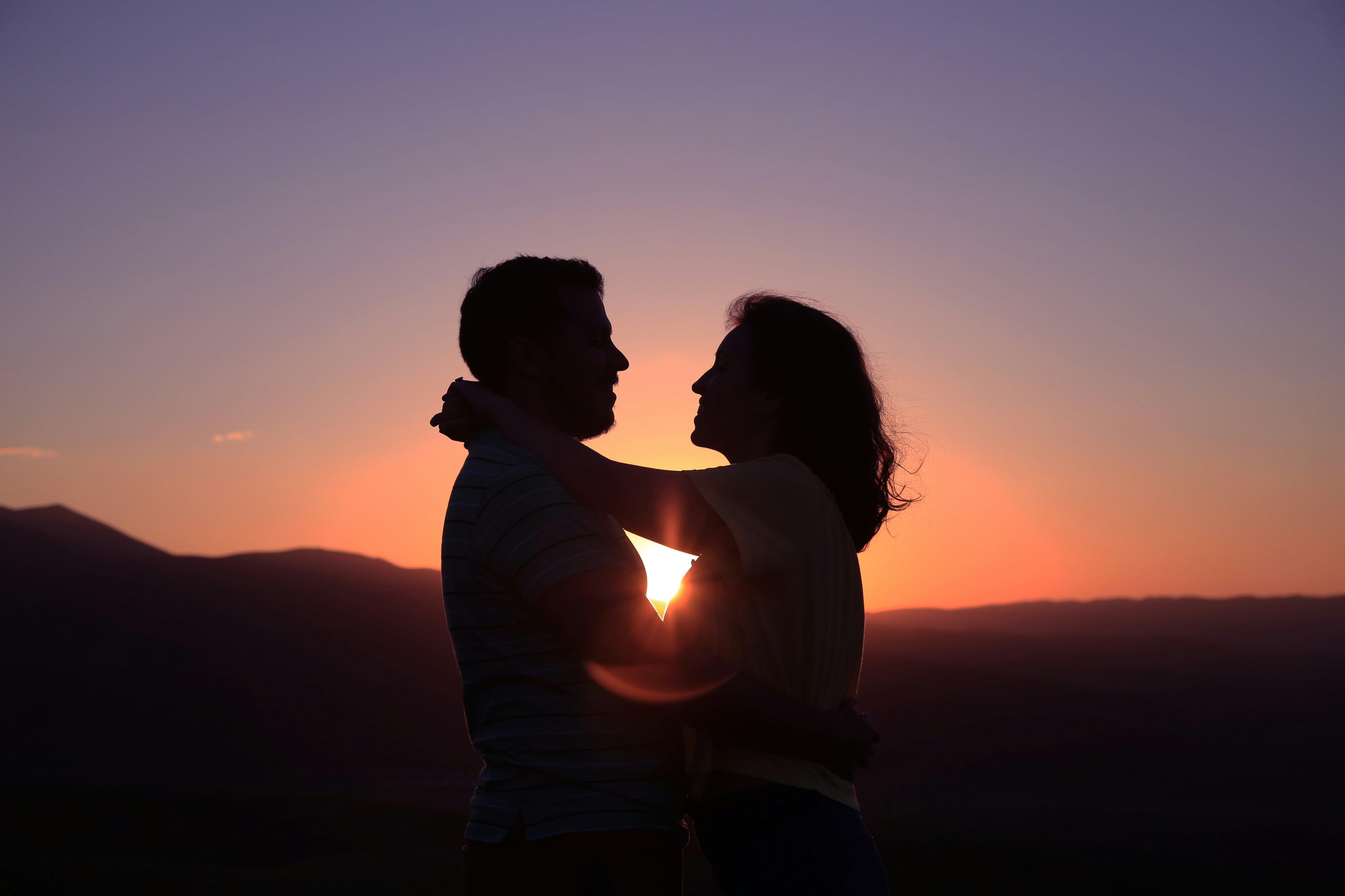 Photo by Oziel Gomez; Woman with her arms around man's neck at sunset