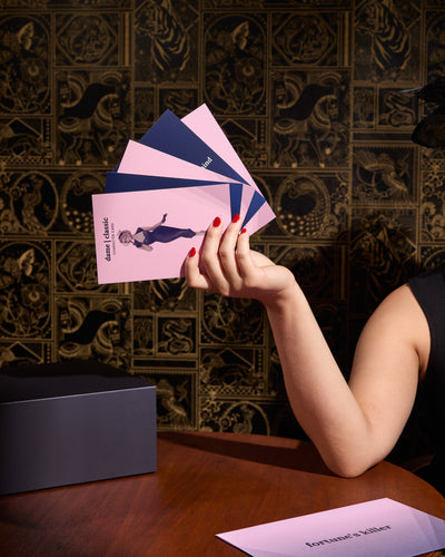 A fan of pink and blue cards held at an angle over a wooden table.