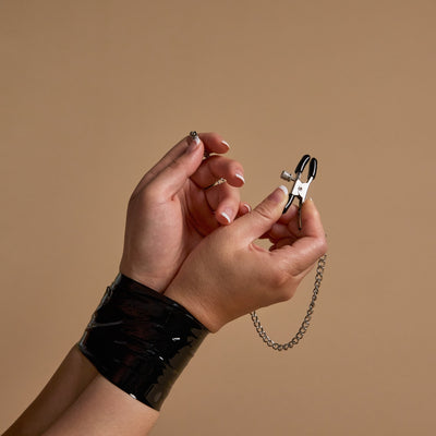 Hands wrapped in black self-adhesive tape, pinching clamp open