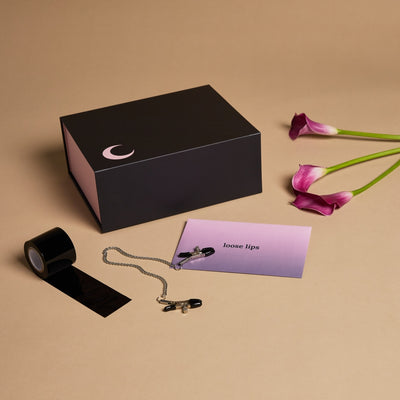 A roll of black self-adhesive tape next to a rectangular box and flowers in the background