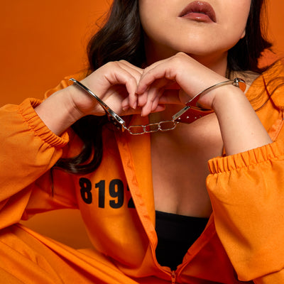Closeup of woman in handcuffs and orange jumpsuit on an orange background