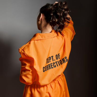 Woman wearing orange jumpsuit from Hard Time set with her back turned