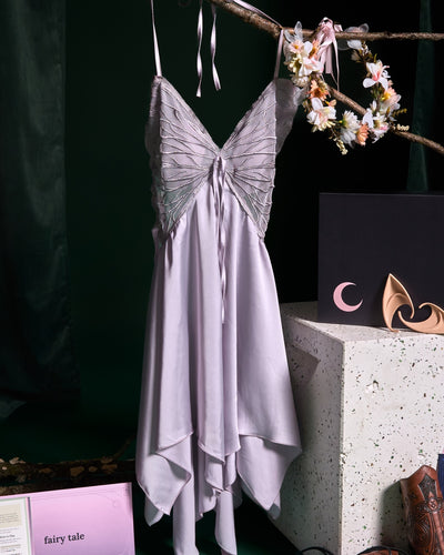 Close-up of purple dress hanging from branch on green background