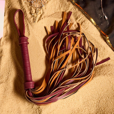 Arabian Nights Tassel Flogger laid flat on sand